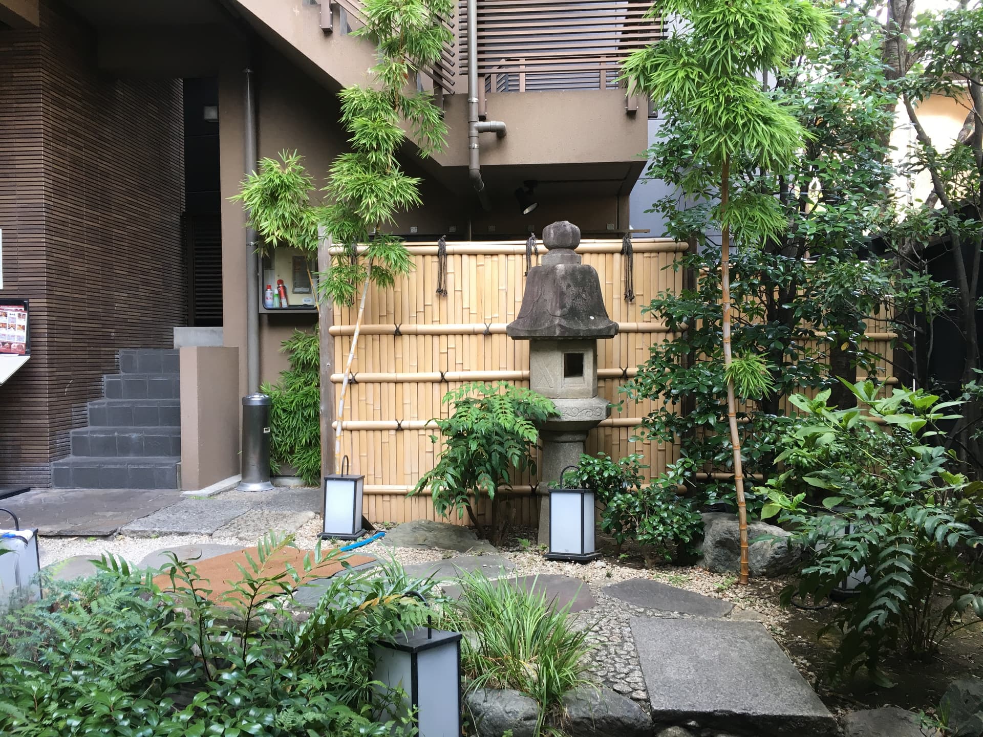 A traditional Japanese ryotei entrance with bamboo fence and stone lantern